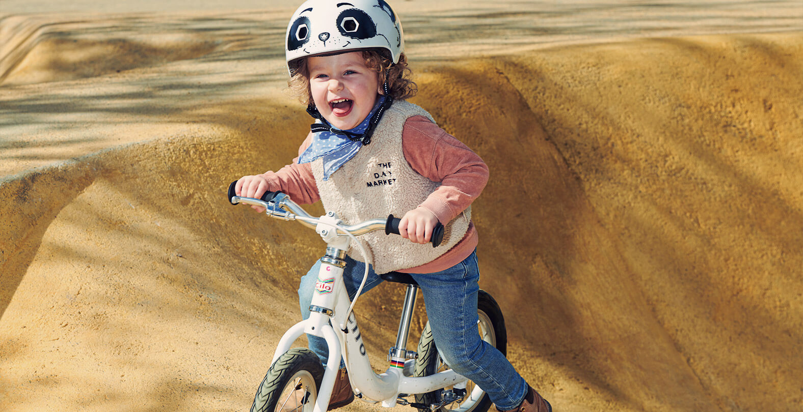 Little child with helmet on a balance bike in the pump track